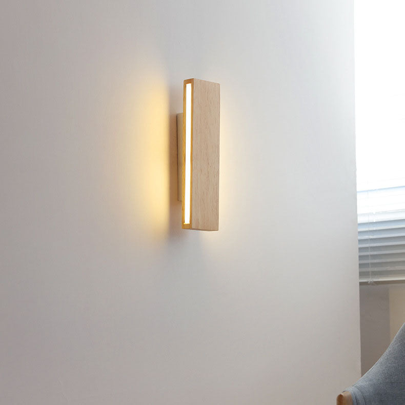 Illuminated vertical wooden bar light on a white wall near a window blind and a grey armchair. 15
