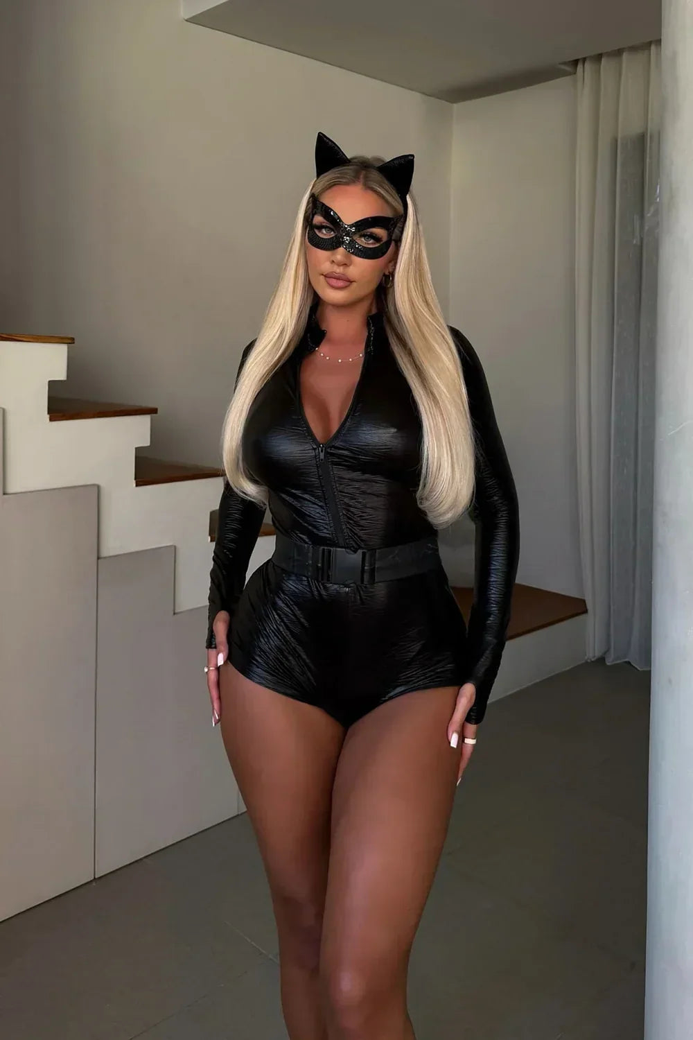 Model with long blonde hair standing indoors in the full costume with mask, ears and belt 6