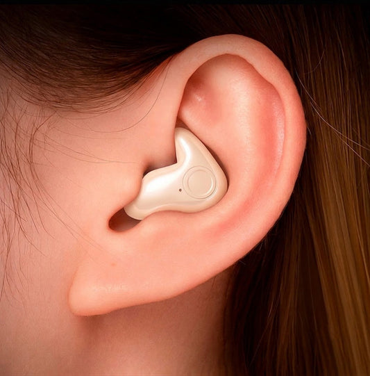 Close-up of a cream-coloured earbud with a round button, worn snugly in an ear 2