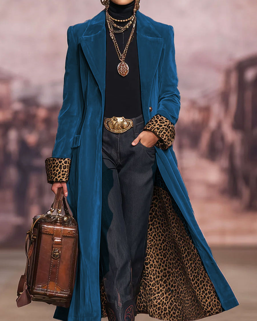 The same coat in a deep teal-blue shade, worn open to show the leopard-print lining and cuffs over a black polo neck. 6