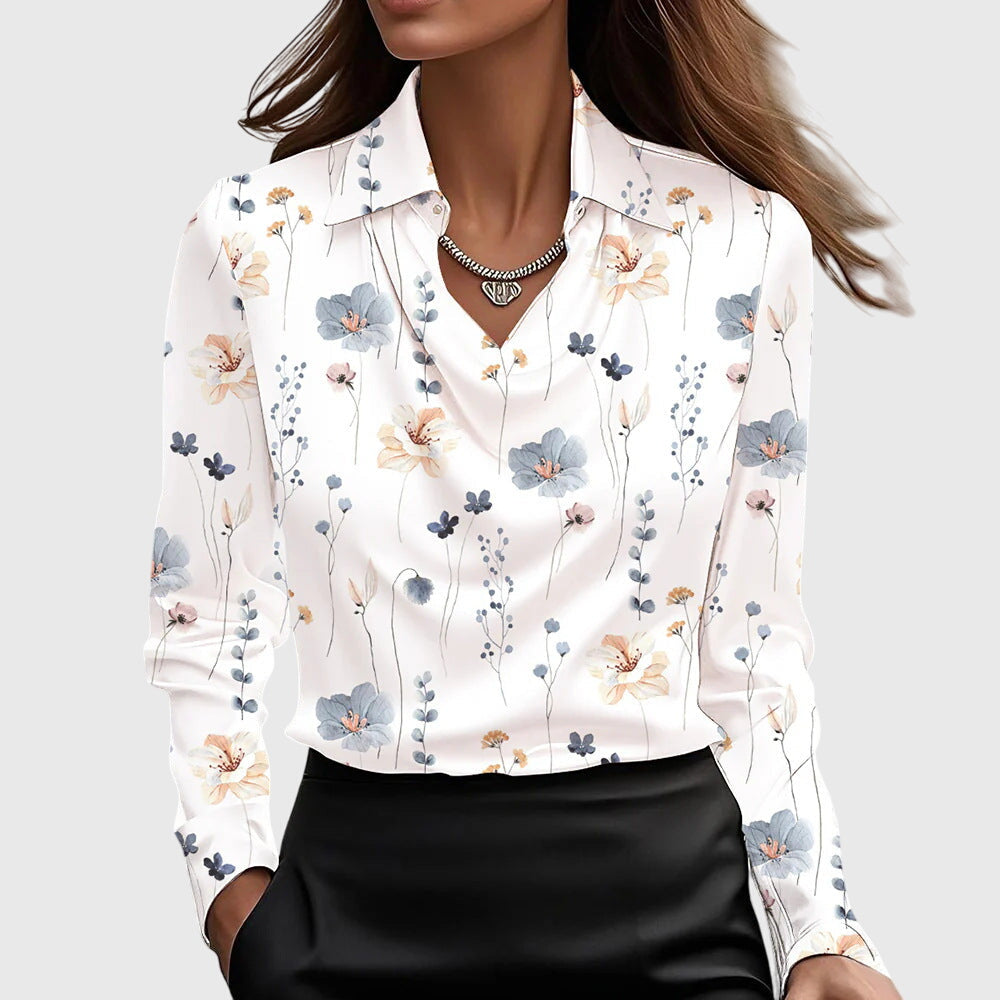Model wearing the white cowl-neck blouse with a scattered print of small blue, peach and pink wildflowers, tucked into a black skirt. 9