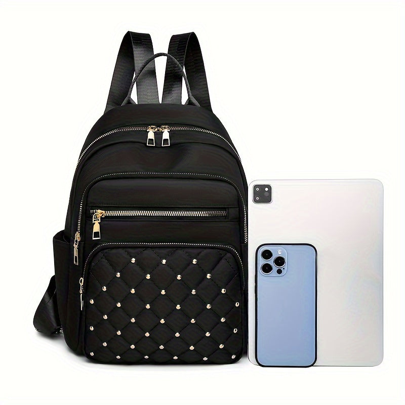 Black backpack standing beside a tablet and a phone, giving a sense of its size 19