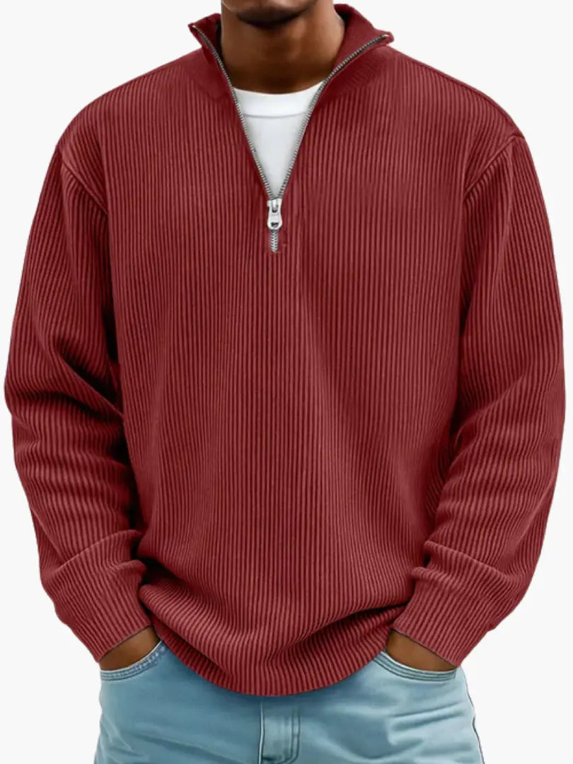 Man wearing the ribbed quarter-zip jumper in brick red over a white tee, hands in the pockets of light blue jeans. 10