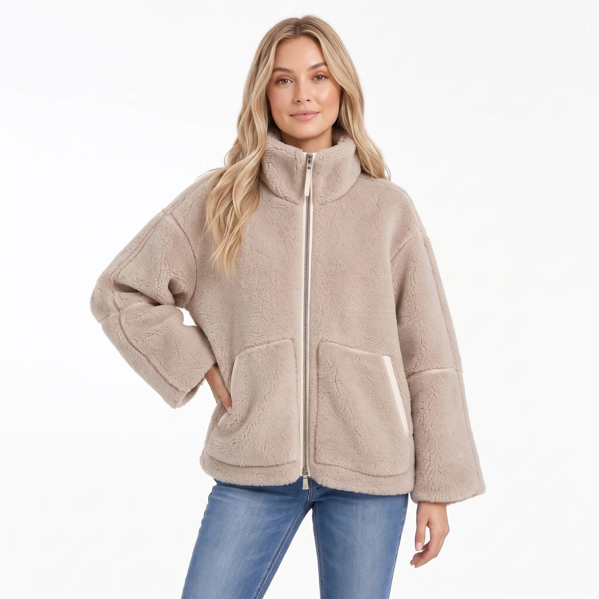Woman in a beige fleece zip coat with cream trim on the pockets and zip, one hand on her hip 9