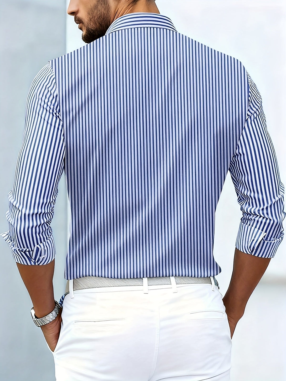 Back view on a model of the blue and white striped shirt, with vertical stripes and white trousers. 8
