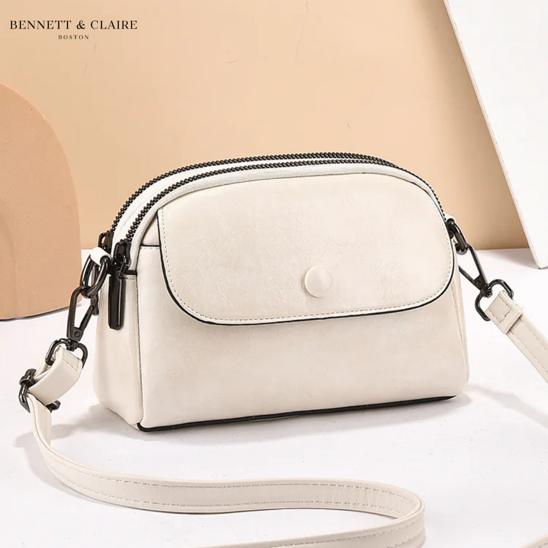 Cream-white version of the crossbody bag with a front flap, round stud fastening, black piping and black metal clasps. 4