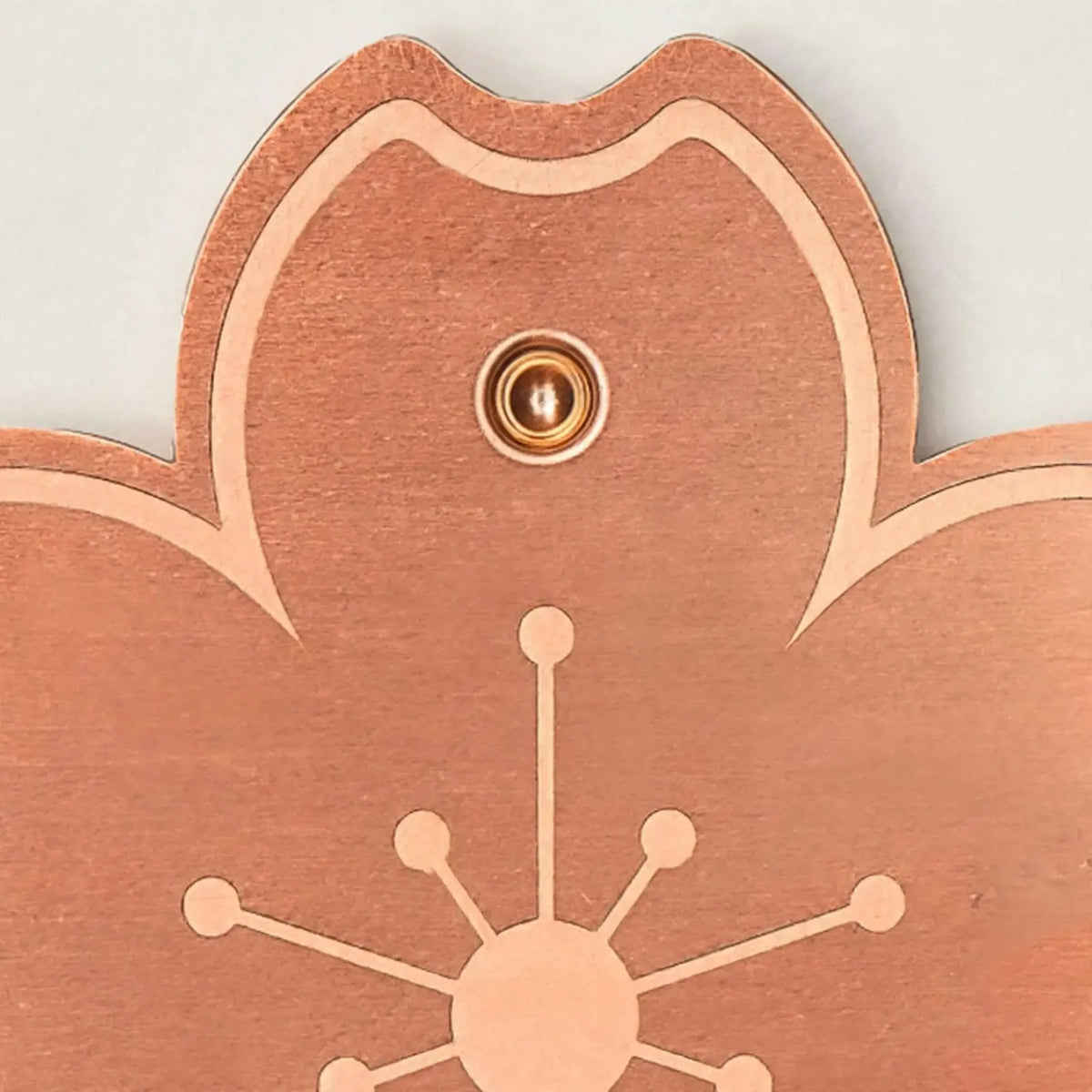 Close-up of one petal of the copper-coloured disc, showing the brushed metal surface, engraved outline and the small round stud. 3