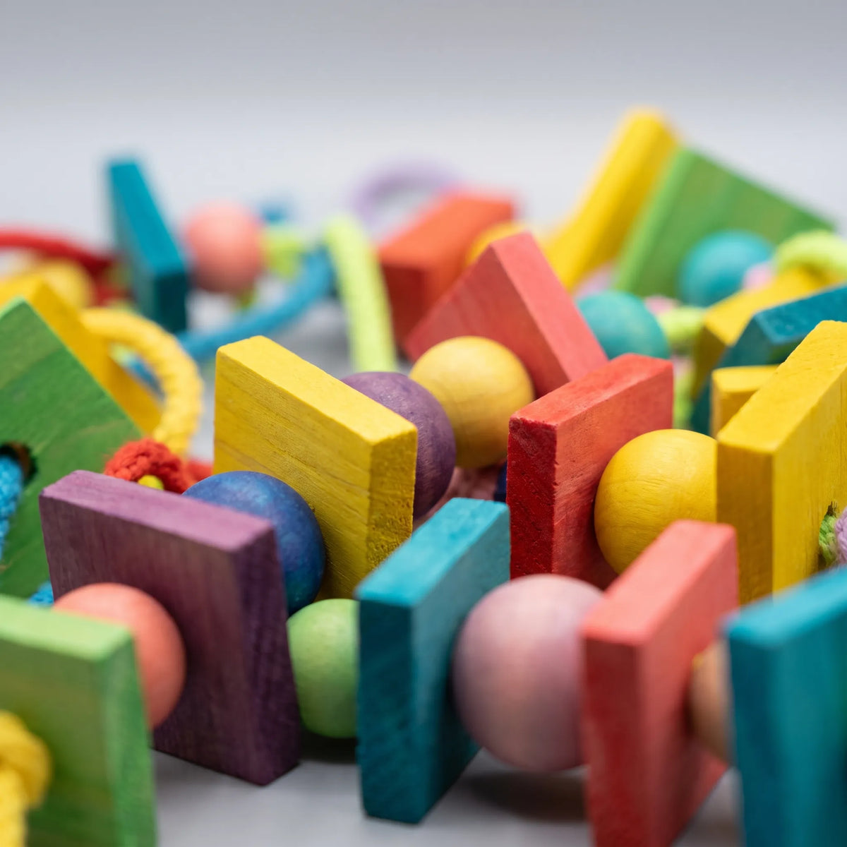 Close-up detail of the dyed wooden blocks and round beads threaded together with braided cotton rope. 4