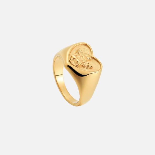 Gold heart signet ring seen from a higher angle, showing the cherub relief on the heart face and the smooth band. 2