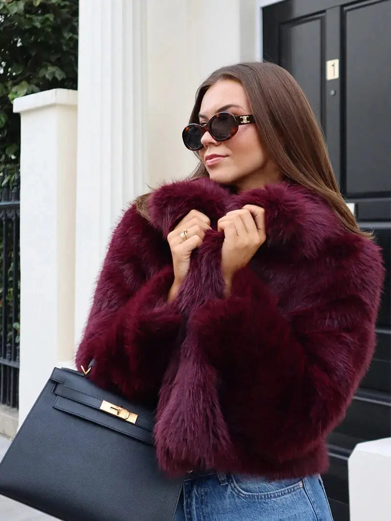Close-up of a woman in sunglasses gripping the wide collar of the burgundy faux fur coat 13