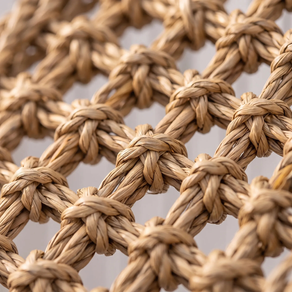 Close-up of the knotted, twisted natural fibres forming the open mesh of the climbing mat. 3