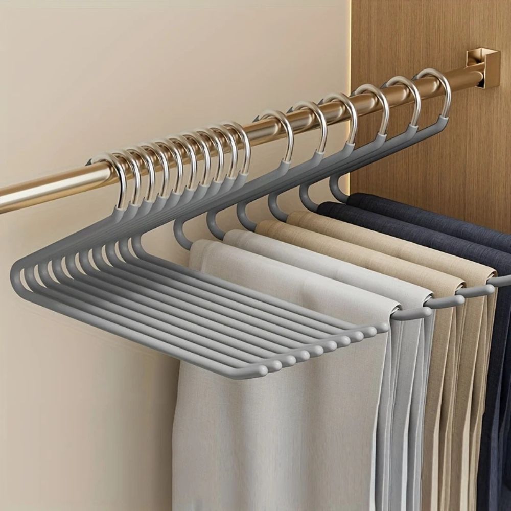Grey Z-shaped hangers on a gold wardrobe rail, holding beige, grey and navy trousers 4