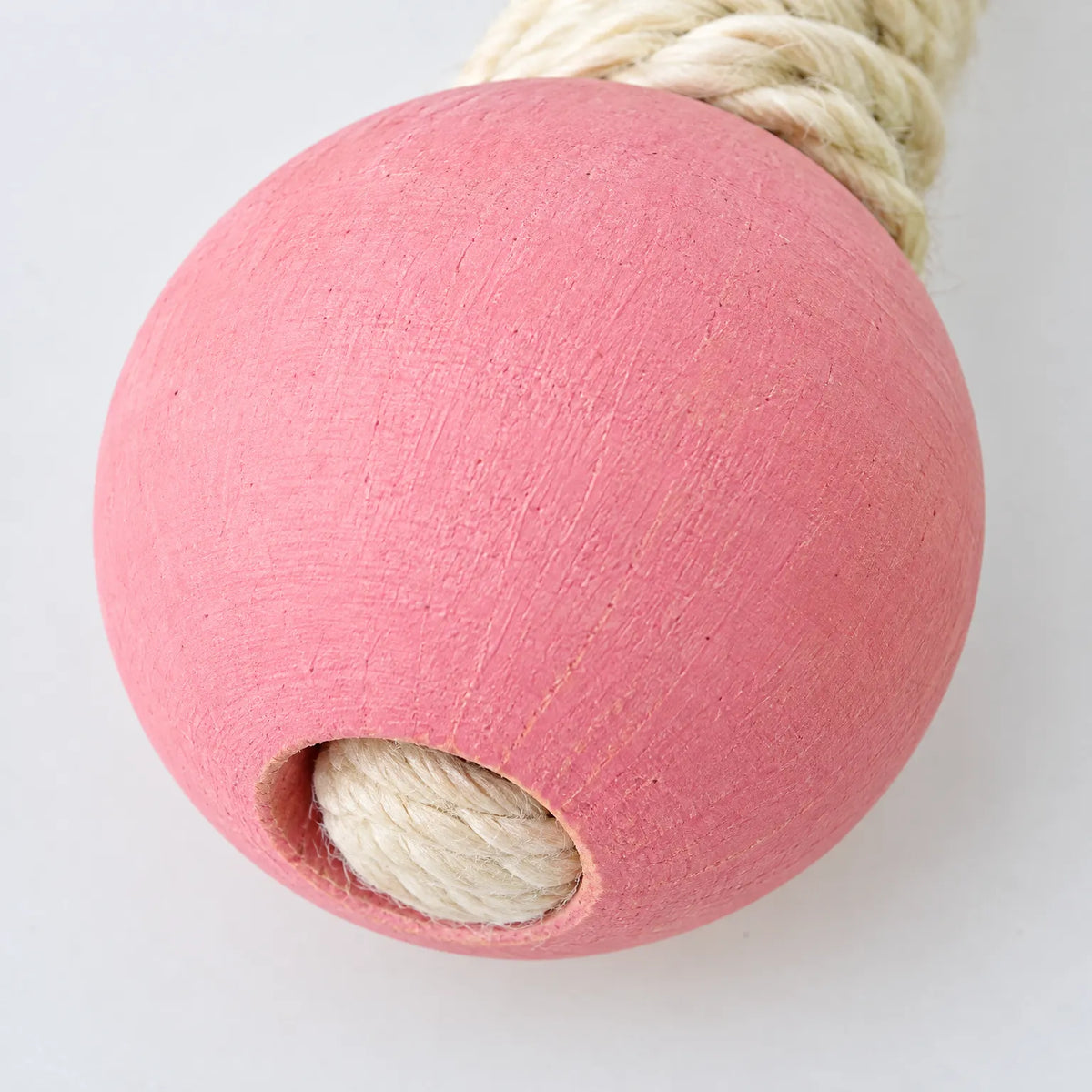 Close-up of one pink painted wooden ball at the end of an arm, showing the cream sisal rope entering its hole. 4