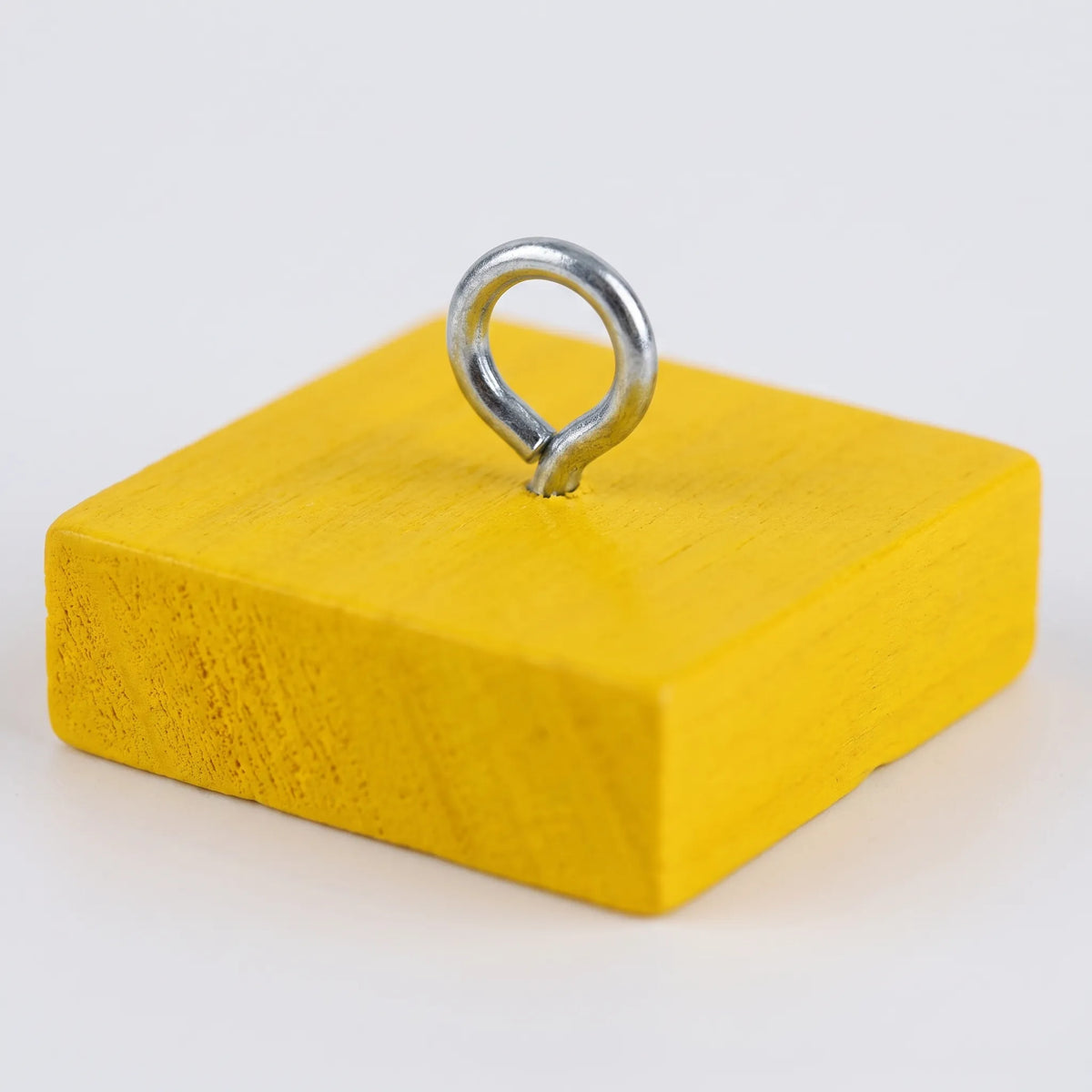 Close-up of a single yellow wooden block with a silver metal eye ring screwed into its top. 3