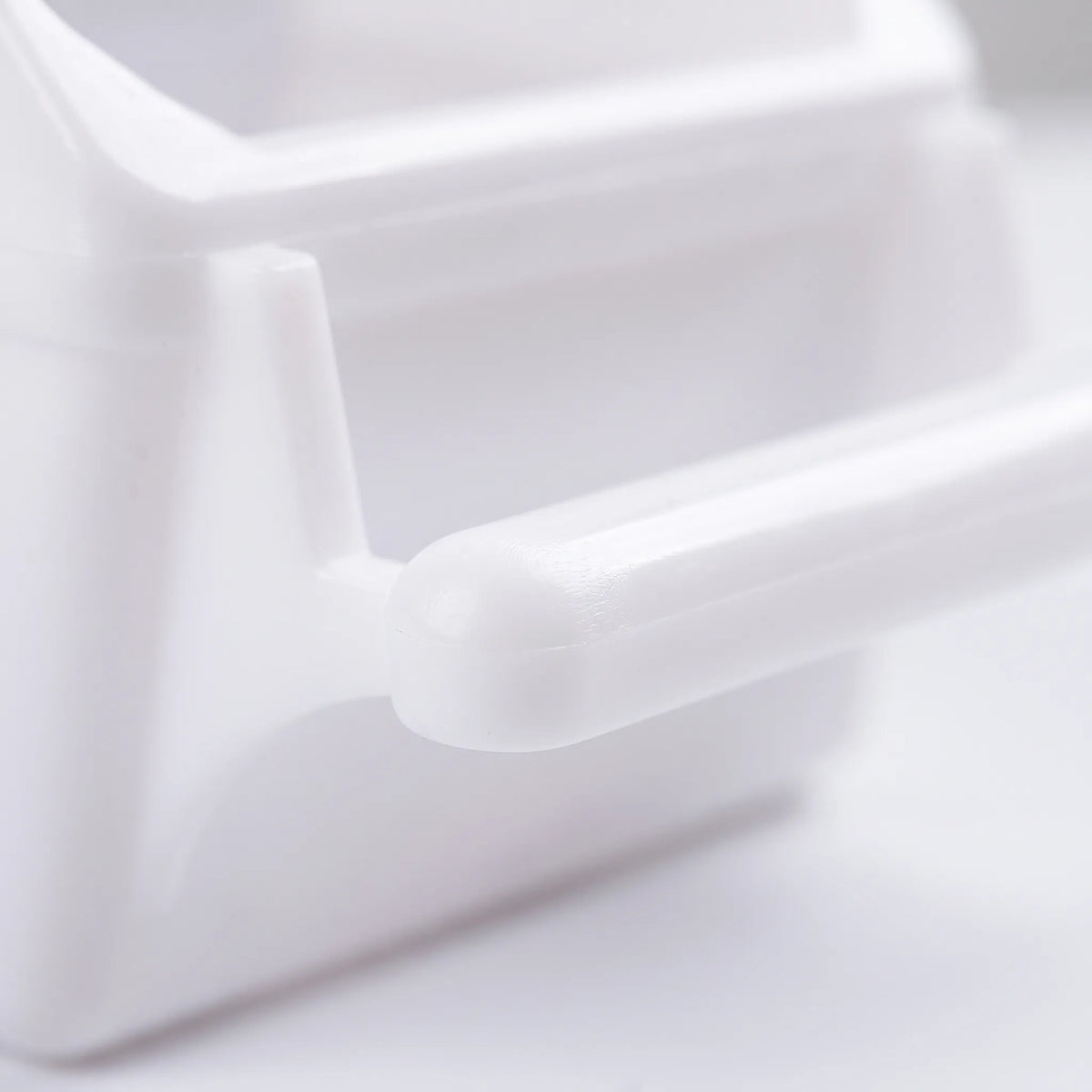 Close-up of the feeder's smooth, rounded white plastic perch and the edge of the seed compartment above it. 4