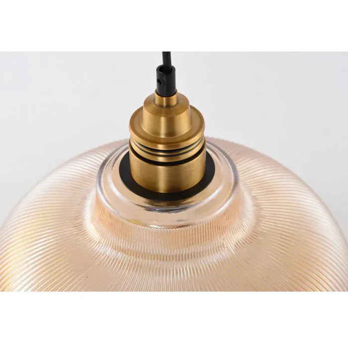 Close-up of the brass lamp holder and black cord where they meet the amber-tinted ribbed glass 6