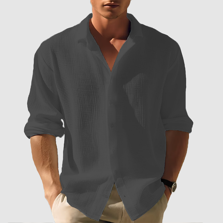 Model wearing the textured shirt in dark charcoal grey, sleeves rolled up, open collar, shown front on with hands in pockets. 7