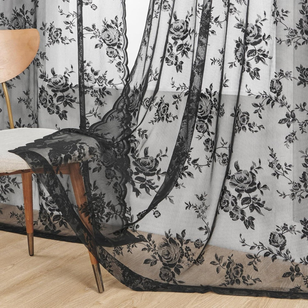 Black rose lace curtain fabric draping to the floor beside a wooden chair, showing the scalloped edge and floral pattern. 12