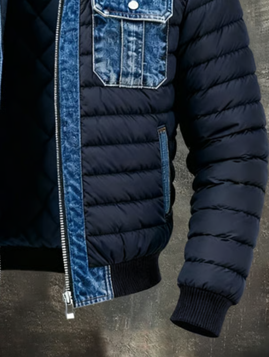 Lower front and sleeve of the jacket showing the padded navy body, denim zip edging, side pocket and ribbed cuff and hem. 5