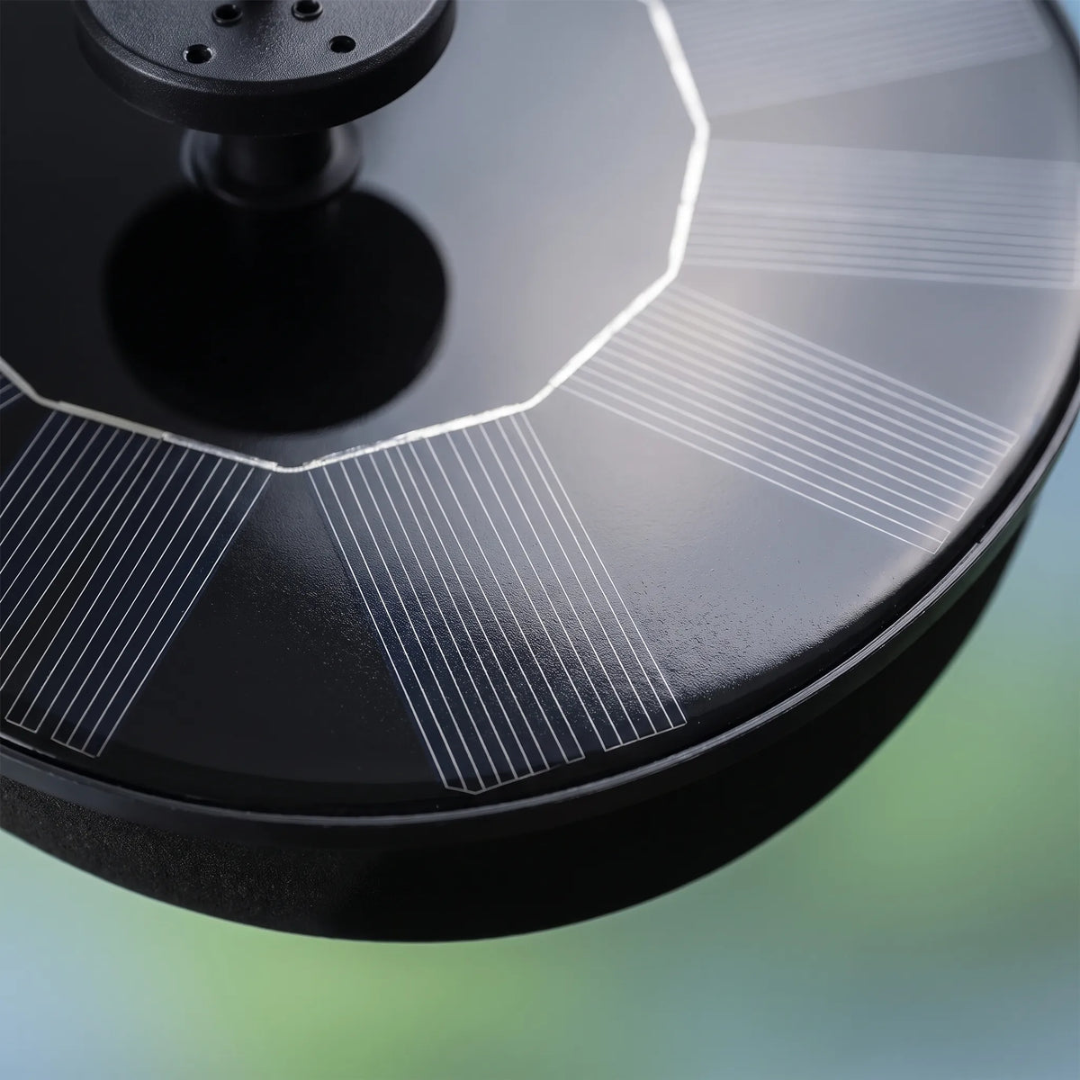 Close-up of the fountain's black solar panel with its fine silver grid lines, the raised nozzle and the rim of the floating base. 3