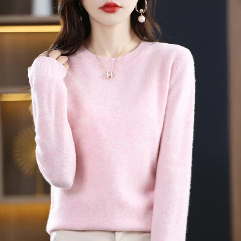 Model wears the soft round-neck jumper in pale pink with cream trousers and a pendant necklace 23