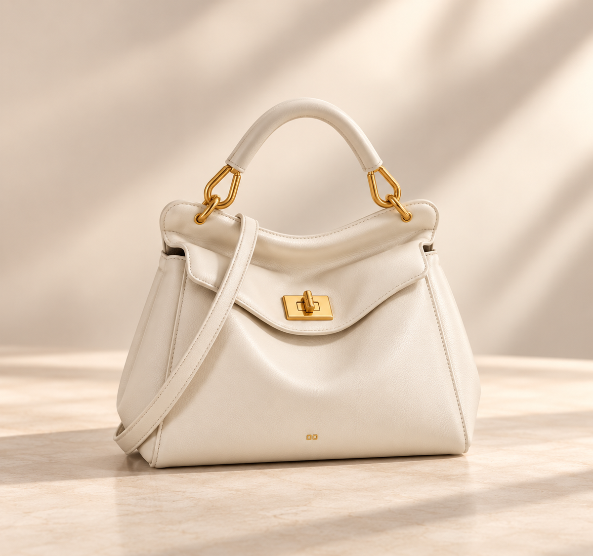 Smooth cream version with gold turn-lock, rolled top handle and crossbody strap, on a pale studio surface 6