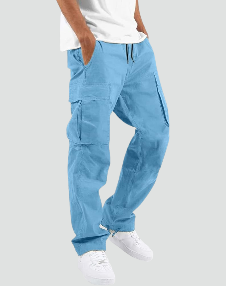 Model wearing light blue cargo trousers with a white t-shirt and white trainers, hand in pocket, angled side view. 14