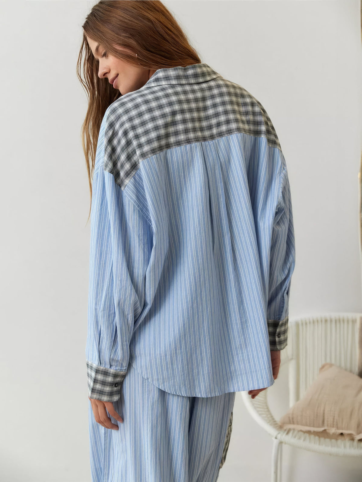 Back view of the blue striped pyjama shirt, with a grey check yoke, collar and cuffs, worn with matching striped trousers. 9