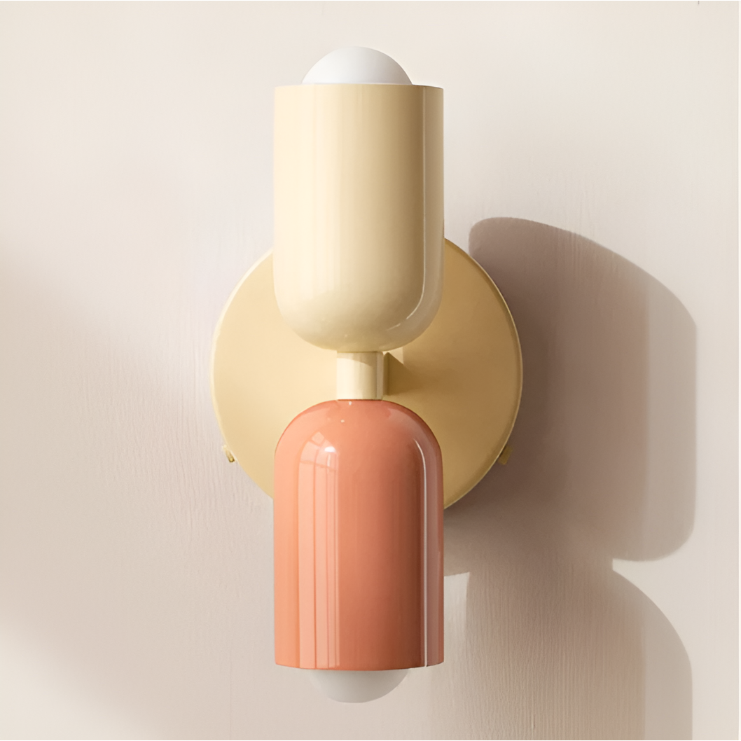 Close-up of the cream and peach wall light, showing the glossy heads, cream backplate and cast shadow. 37