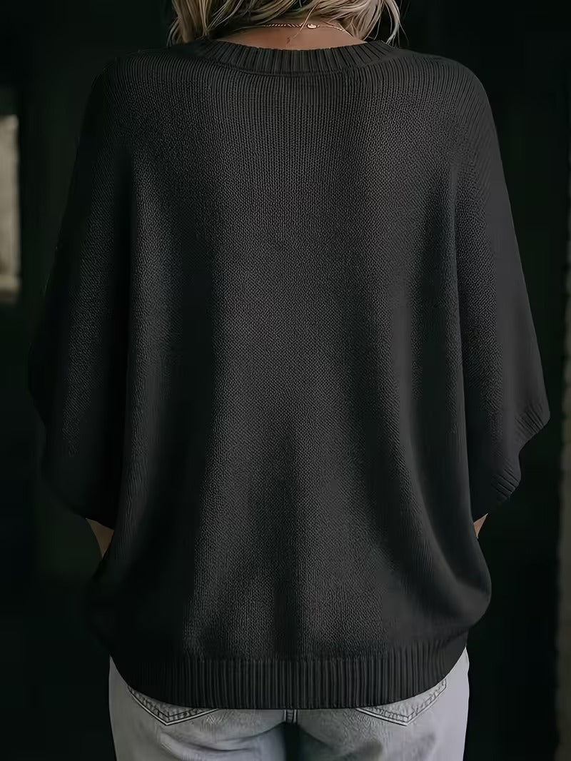 Back view of the black batwing knit top, showing the round neckline, wide short sleeves and ribbed hem. 28