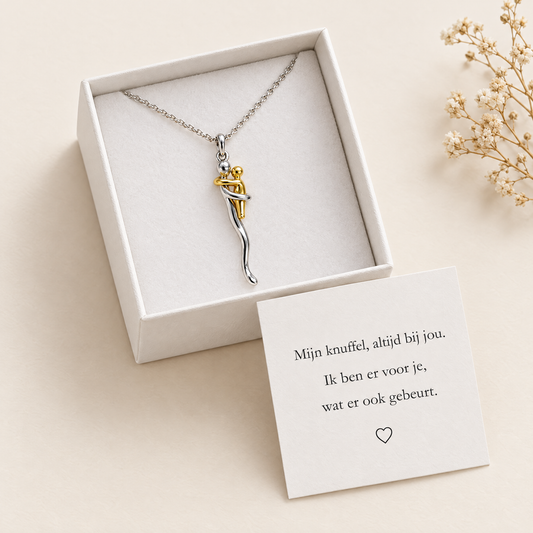 Necklace lying in an open white gift box with a printed message card beside it and dried flowers nearby. 2