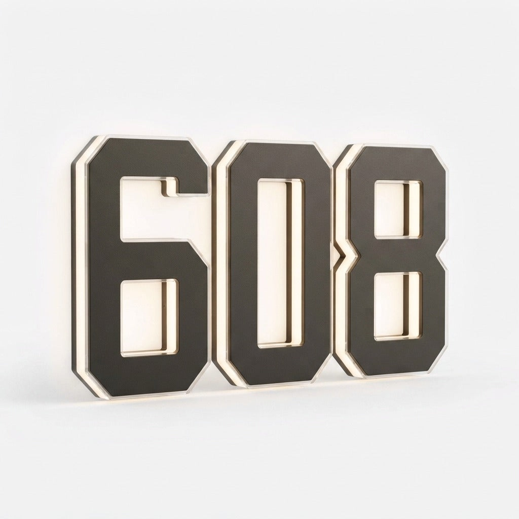 Three black digits spelling a house number on a plain white background, shown at an angle to reveal the layered edges and soft backlight. 19