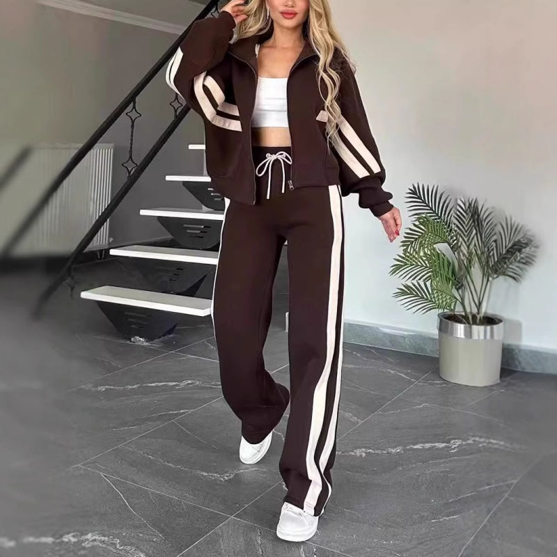 Model walking in the dark brown set with cream stripes, zip jacket worn open and wide-leg drawstring trousers. 8