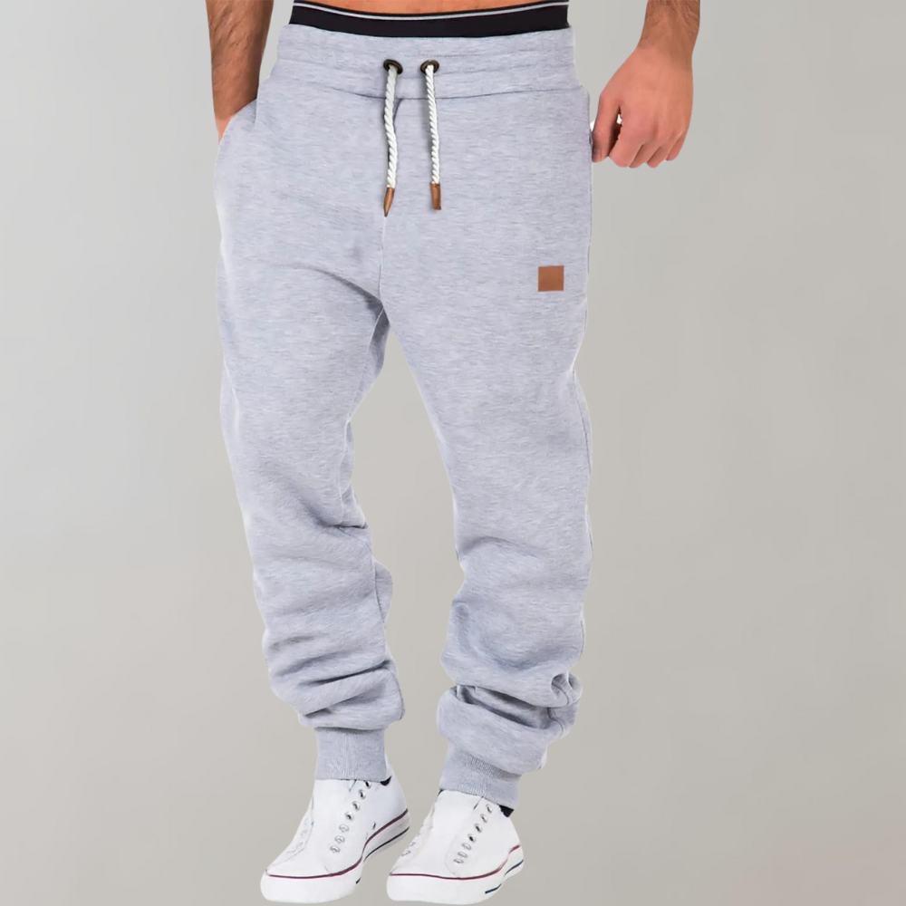 Light grey joggers on a model with white trainers, hand in pocket, ribbed ankle cuffs 4