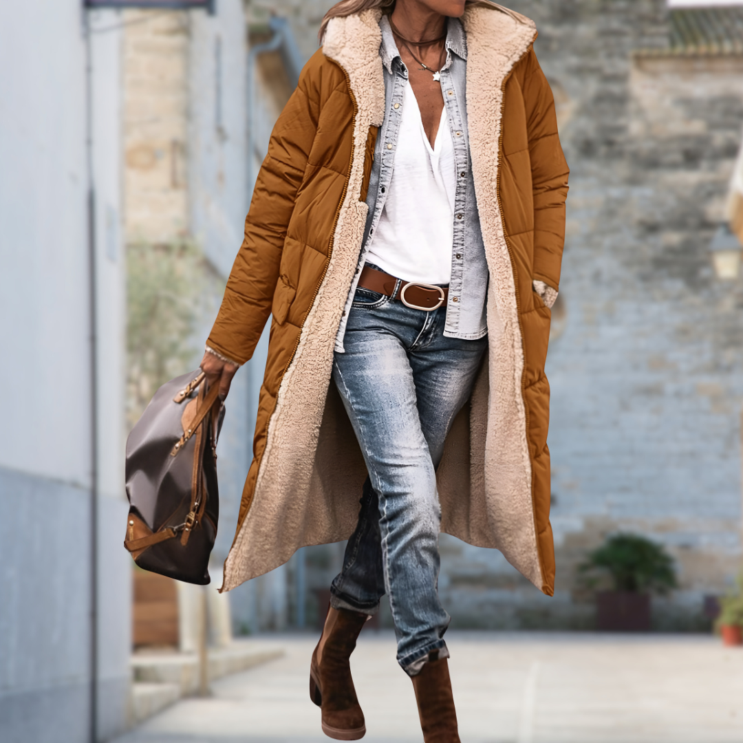 Woman walking outdoors in the long tan quilted coat, worn open to show the cream fleece lining and hood. 9