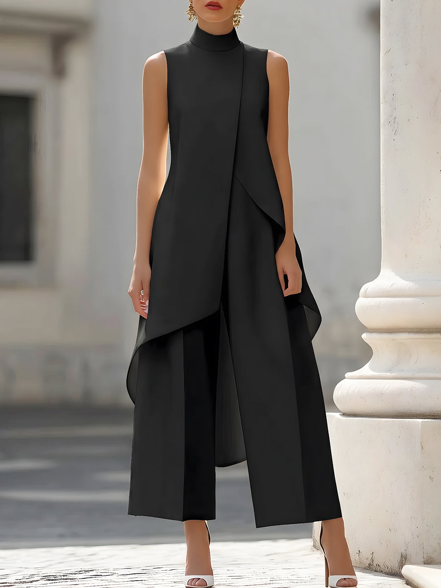 Front view in black on a model by a white stone column, showing the high neck and sweeping asymmetric hem. 2