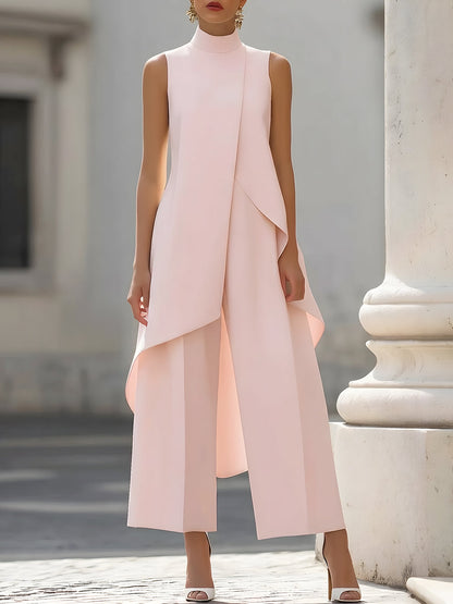 Front view in soft pink on a model beside a stone column, with the draped asymmetric hem over wide trousers. 7
