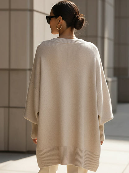 Back view of the cream knit poncho, showing the ribbed hem and wide draped sleeves 5