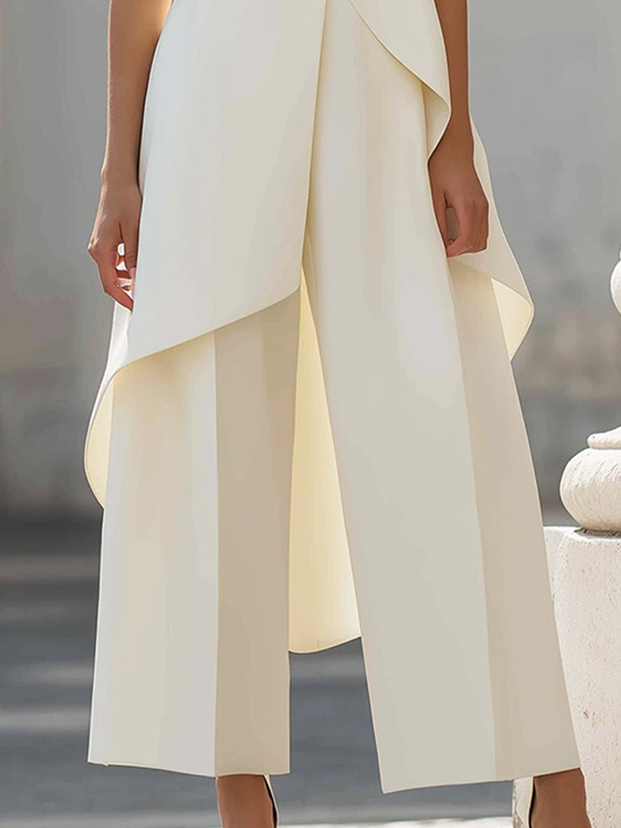 Close-up of the cream wide-leg trousers with front creases, partly covered by the flowing hem of the top. 12
