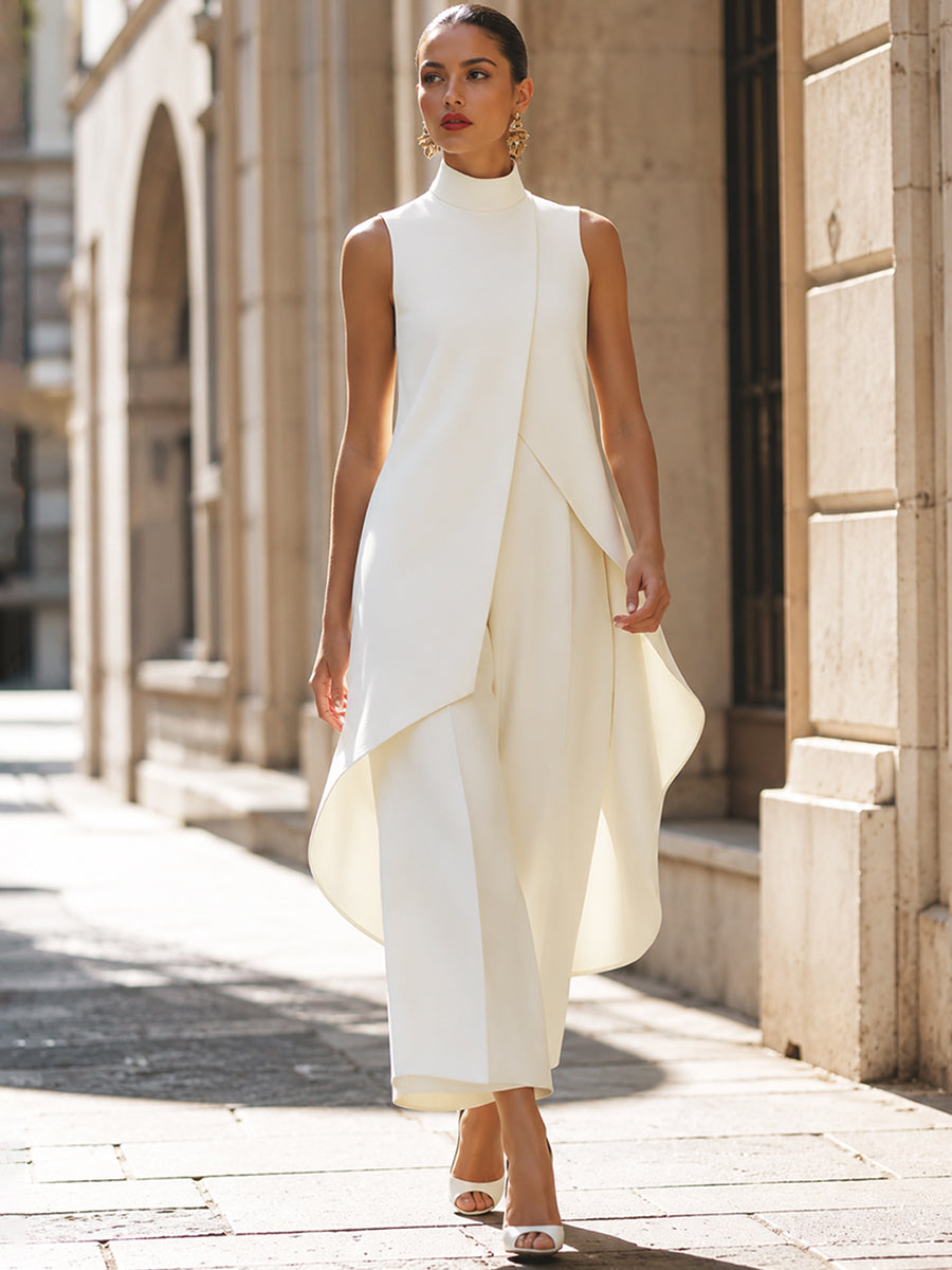 Model walking along a sunlit stone street in the cream set, the curved asymmetric hem swinging as she moves. 9