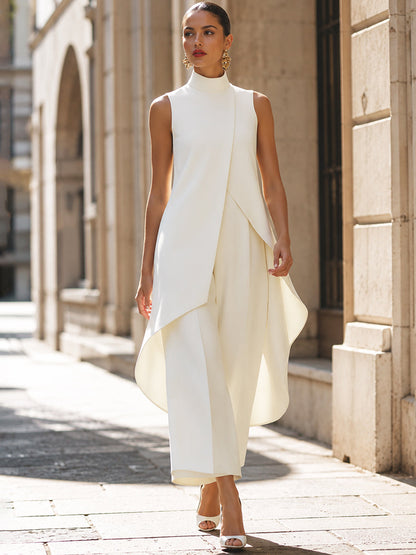 Model walking along a sunlit stone street in the cream set, the curved asymmetric hem swinging as she moves. 9
