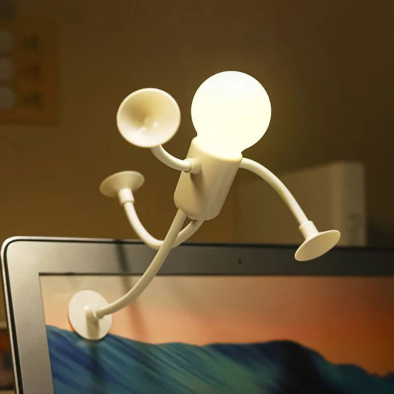White glowing figure lamp stuck by its suction cups to the edge of a laptop screen like a climber. 7