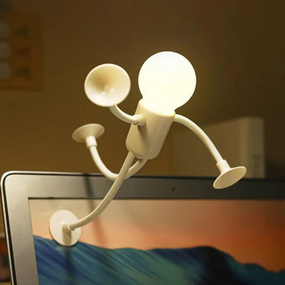 White glowing figure lamp stuck by its suction cups to the edge of a laptop screen like a climber. 7