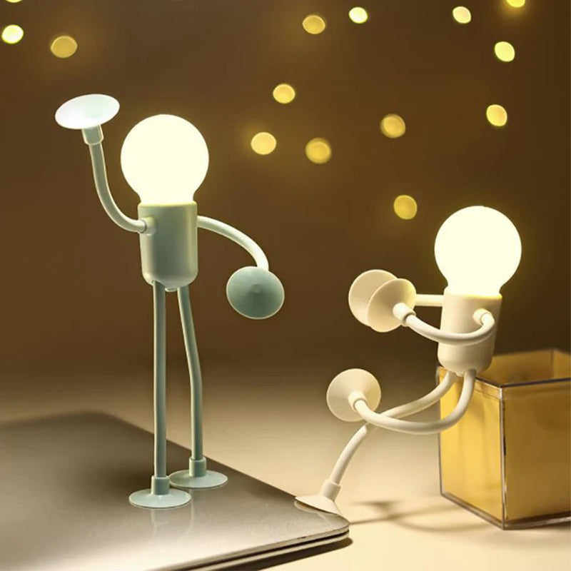 Green figure lamp stands with one arm raised on a laptop while a white one sits on a clear box, bokeh lights behind. 8