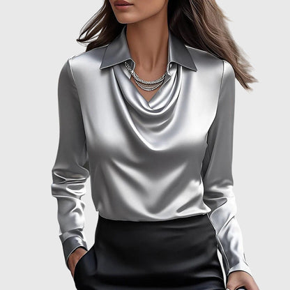 Model wearing the glossy satin cowl-neck blouse in silver-grey with a pointed collar and long sleeves, paired with a black skirt. 2
