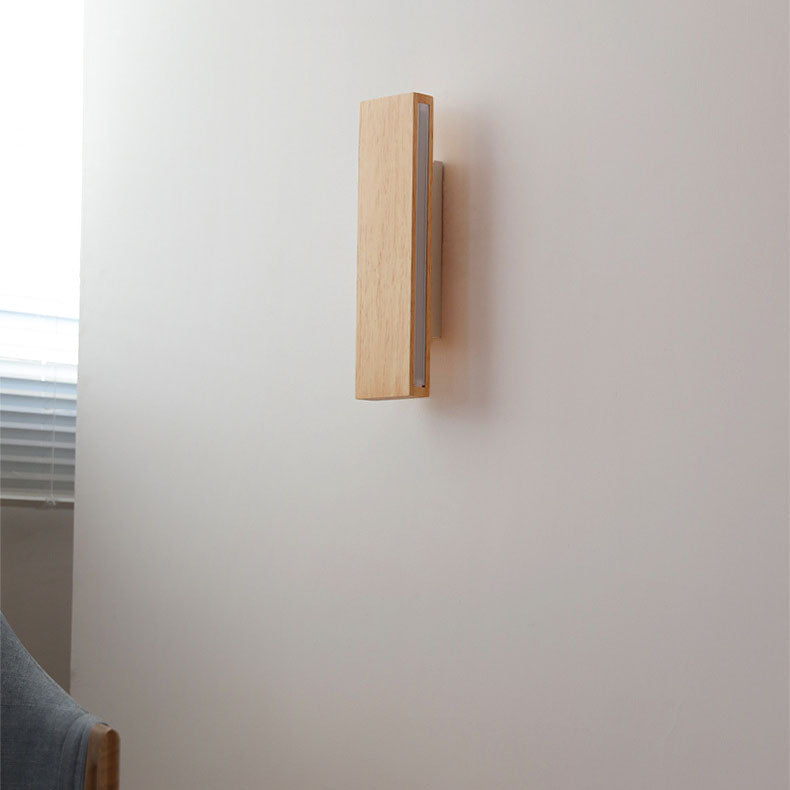 Side view of the unlit wooden bar light mounted vertically on a pale wall beside a window blind. 2