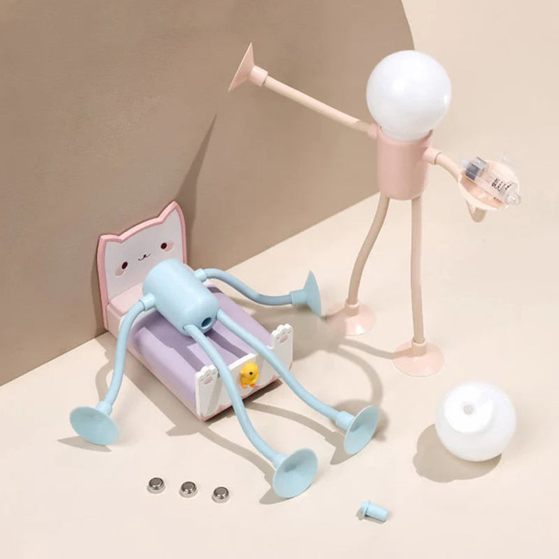 Playful scene with a pink figure lamp holding a small part beside a blue one on a toy cat bed, with spare batteries and bulb. 13