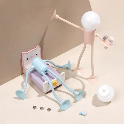 Playful scene with a pink figure lamp holding a small part beside a blue one on a toy cat bed, with spare batteries and bulb. 13