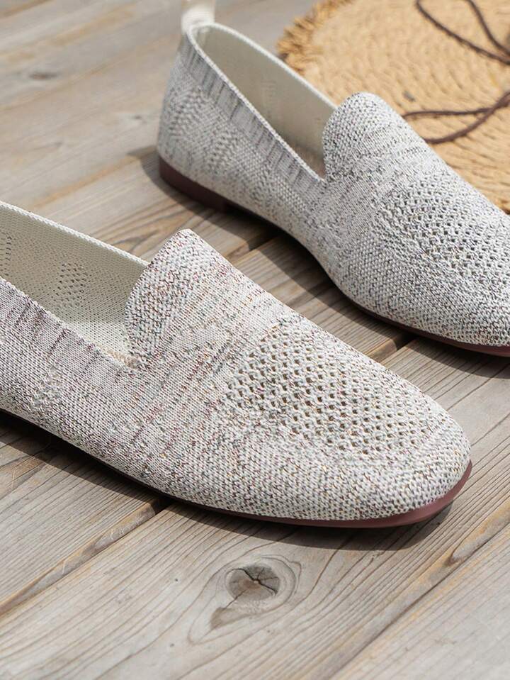 Close-up of light grey knit slip-ons on wooden boards, showing the speckled texture and perforated toe area. 16