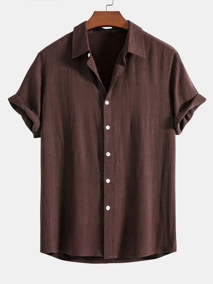 Short sleeve button-up shirt in dark chocolate brown on a wooden hanger, with cuffed sleeves and white buttons. 8